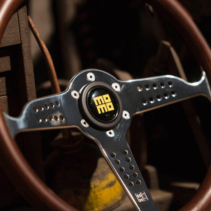 Steering wheel with a prominent logo in the center, set against a blurred background.