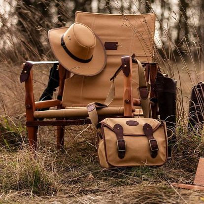 Vintage hunting scene with chair, bag, and rifles in a natural setting